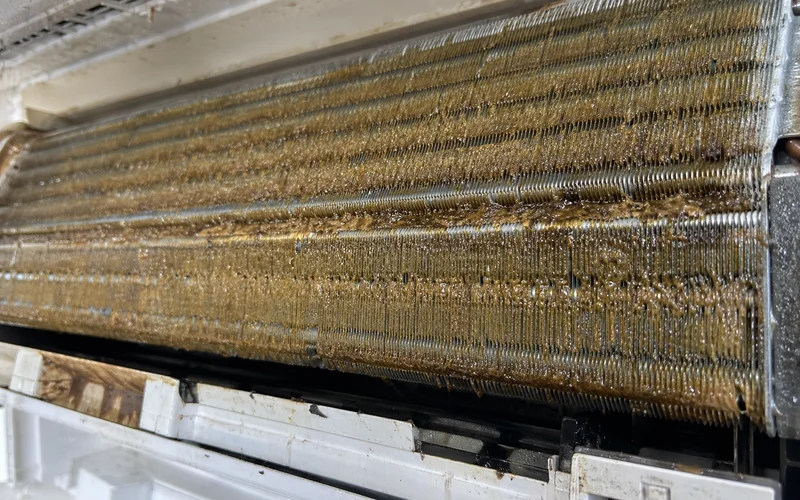 Close-up of aircon fin caked with yellow-brown grease deposit